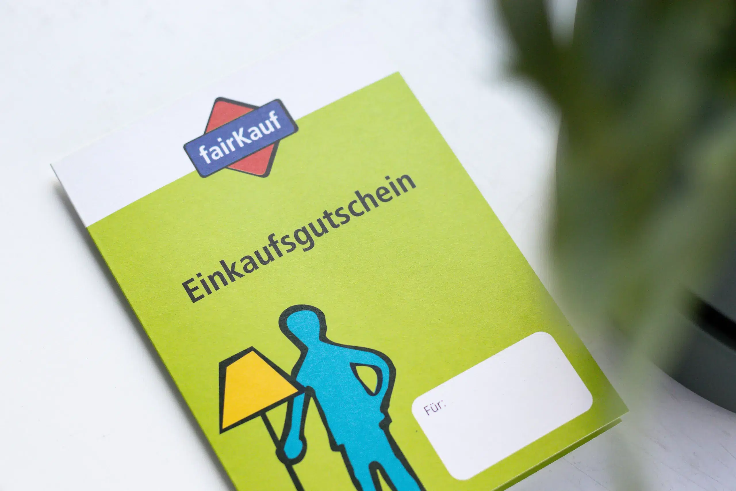 Ein Einkaufs­gutschein von fairKauf mit einem grafischen Symbol einer Person, die eine Lampe hält.