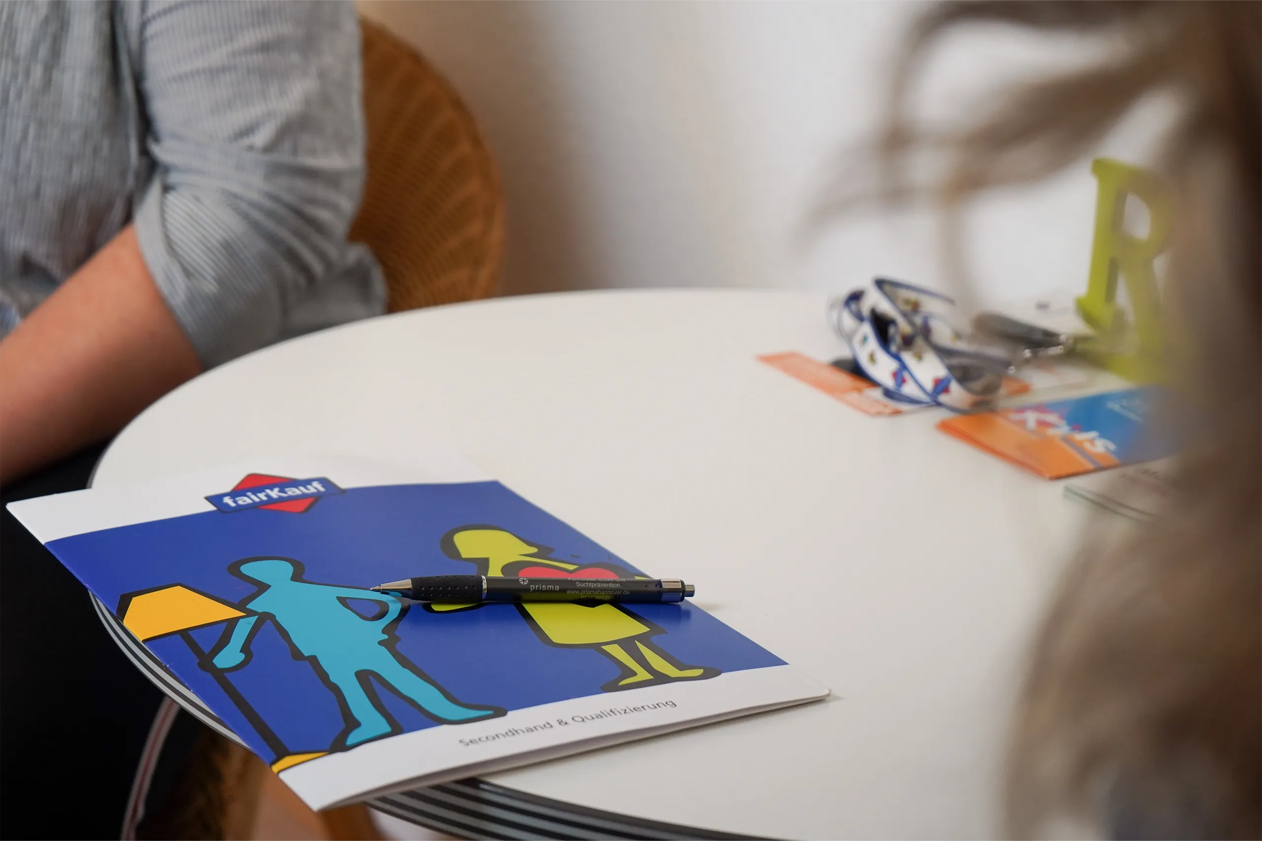 Broschüre und Stift auf rundem Tisch während eines Beratungsgesprächs.