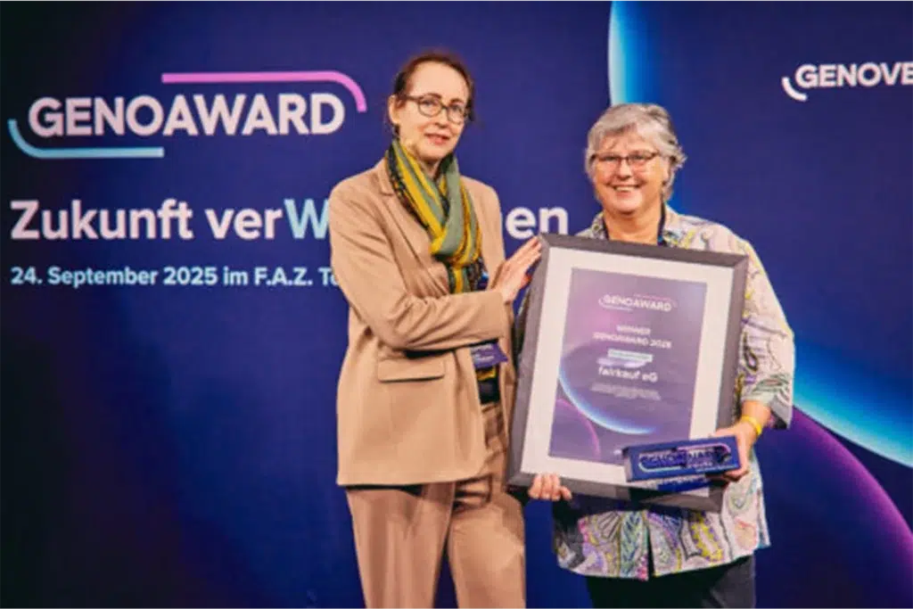 Zwei Personen präsentieren auf einer Bühne den Genoaward für Fairkauf eG vor einem bunten Hintergrund mit Schriftzug „Zukunft verWegen“.