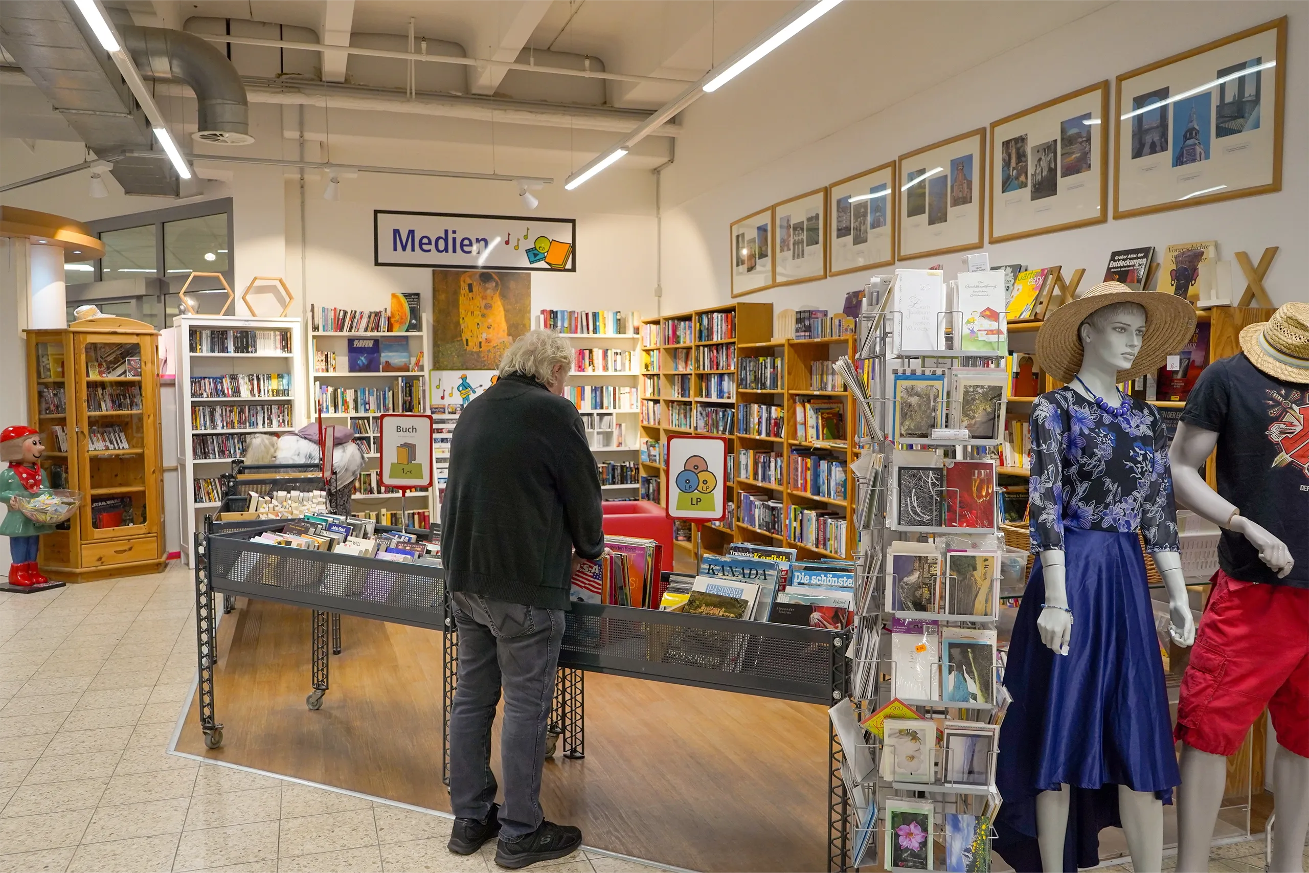 Ein Mann stöbert in einer Medienecke mit Büchern und Zeitschriften in einer Bibliothek.